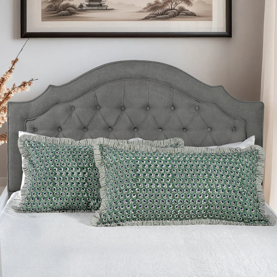 Large block print cotton pillows styled on gray upholstered bed.
