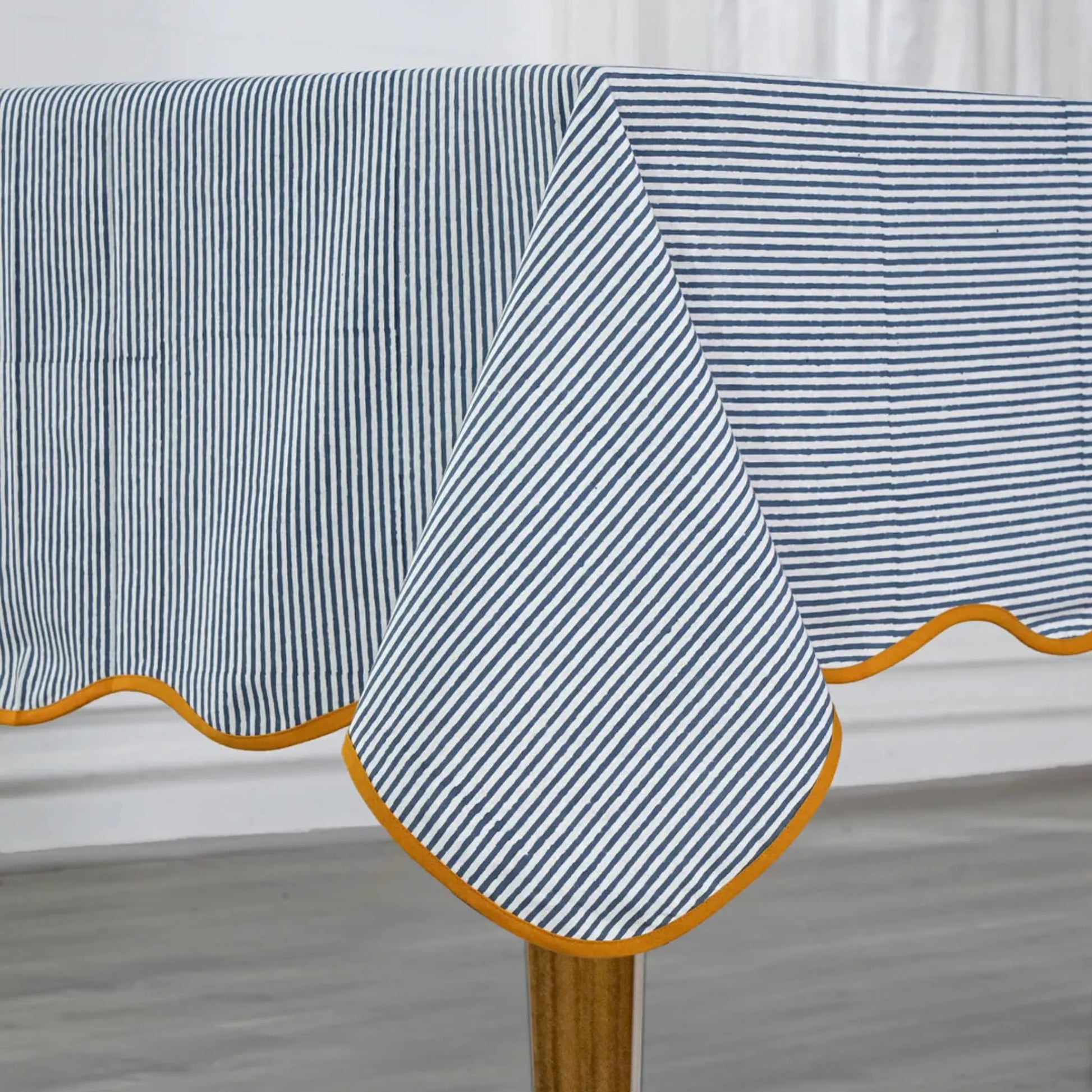 Striped tablecloth with a yellow border on a wooden table.