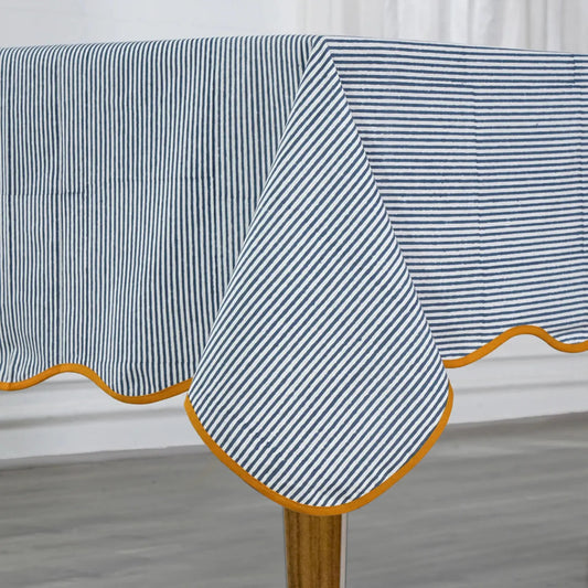 Striped tablecloth with a yellow border on a wooden table.