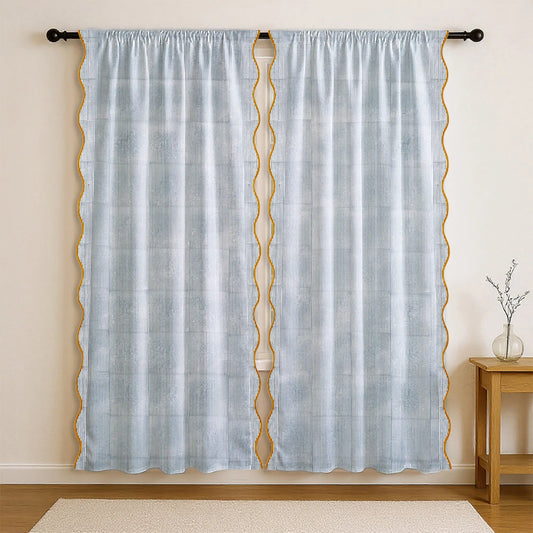 Light blue curtain with gold geometric patterns on a beige wall.