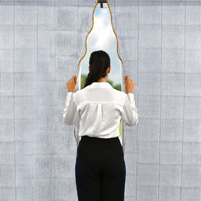 Person holding a unique mirror with a geometric design against a textured wall.