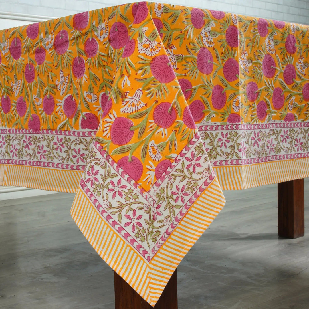 Colorful floral-patterned tablecloth on a wooden table with a white background