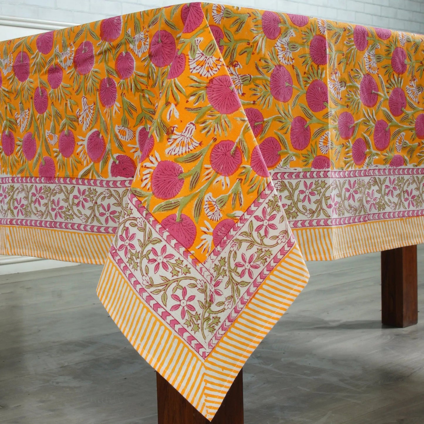 Colorful floral-patterned tablecloth on a wooden table with a white background