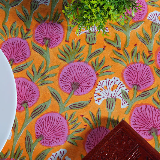 Patterned fabric with pink flowers and green leaves on an orange background
