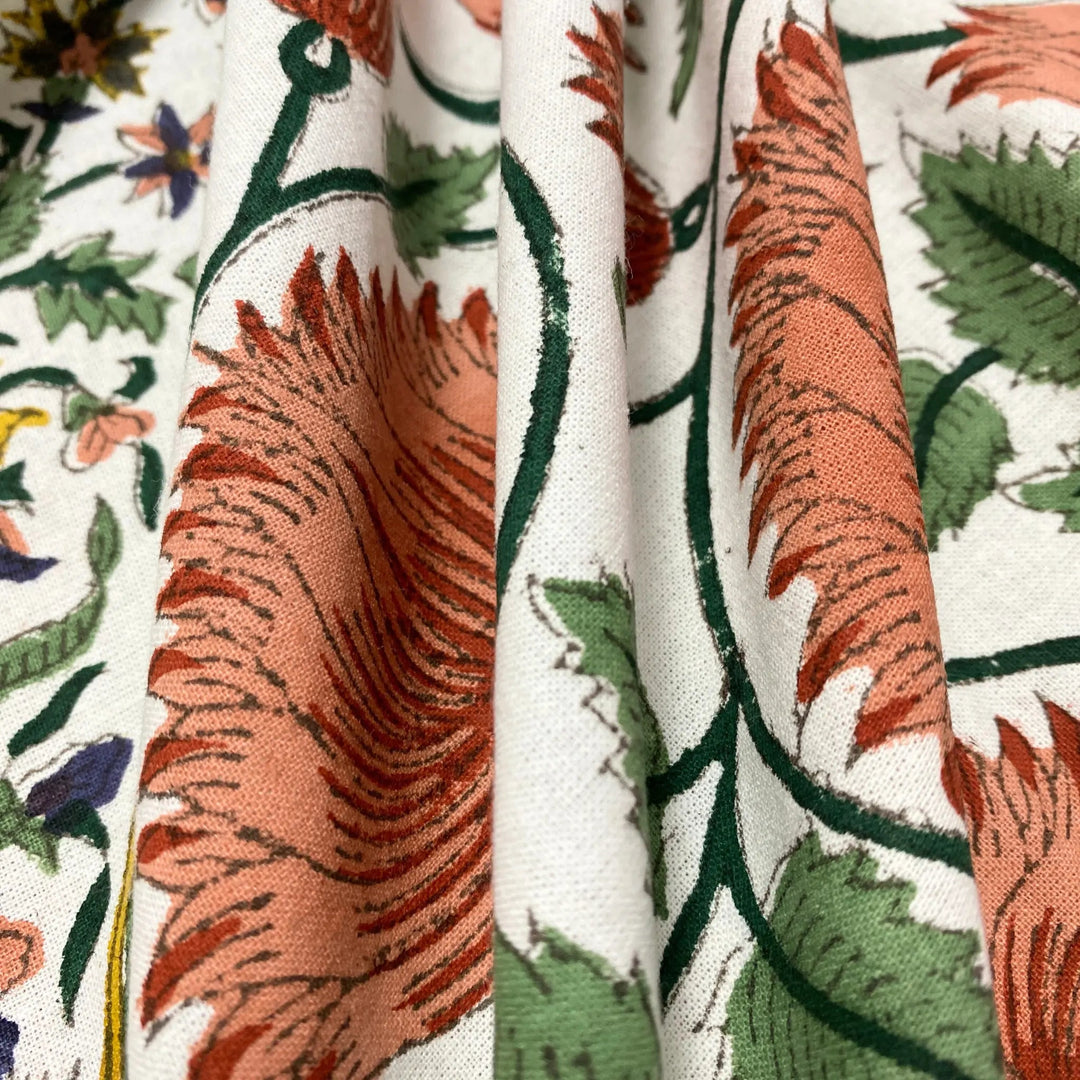 Close-up of floral fabric with orange, green, and red patterns on a white background