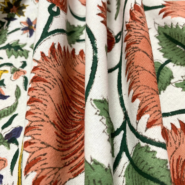 Close-up of floral fabric with orange, green, and red patterns on a white background