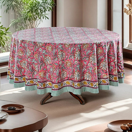 Round table with a floral patterned tablecloth in a bright room with plants.