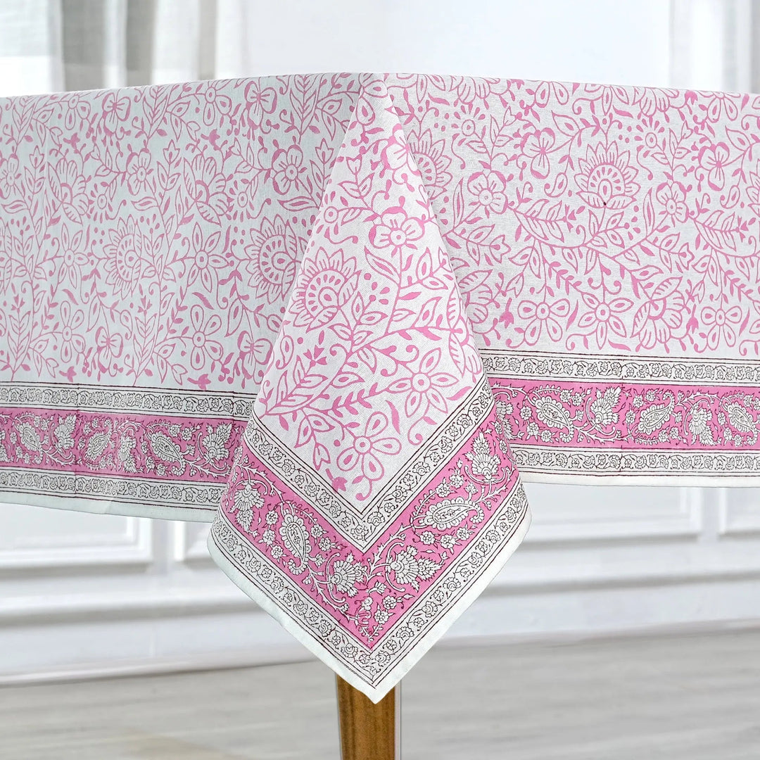 Pink and white patterned tablecloth on a wooden table with a white curtain background