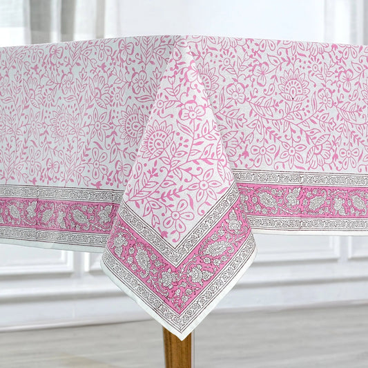 Pink and white patterned tablecloth on a wooden table with a white curtain background