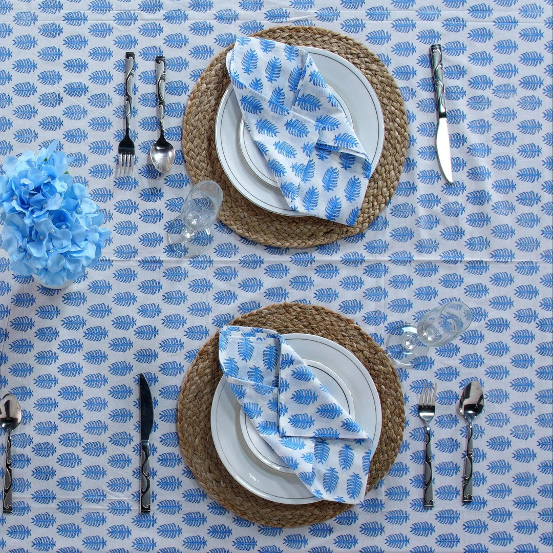 Table setting with blue and white patterned napkins on a blue tablecloth.