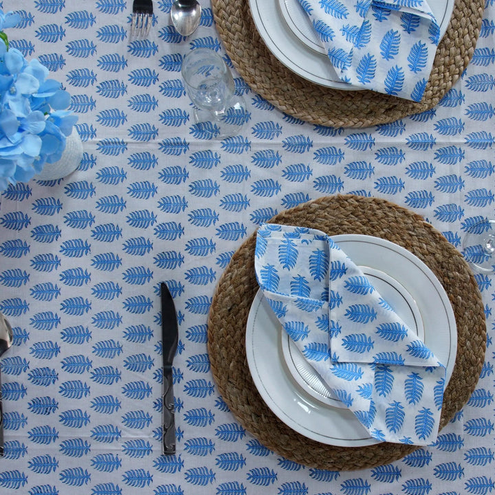 Table setting with blue and white patterned tablecloth, plates, and cutlery.
