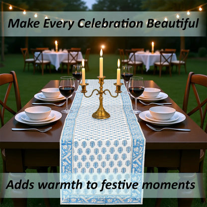 Dining table set for a celebration with a decorative table runner, candles, and wine glasses.