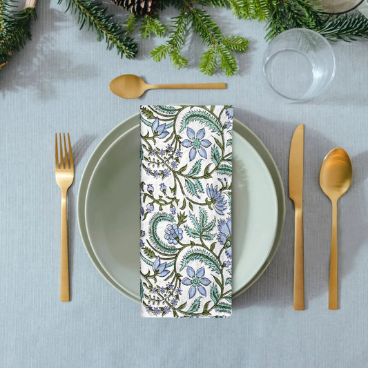 Napkin with floral pattern on a table setting with cutlery and greenery.