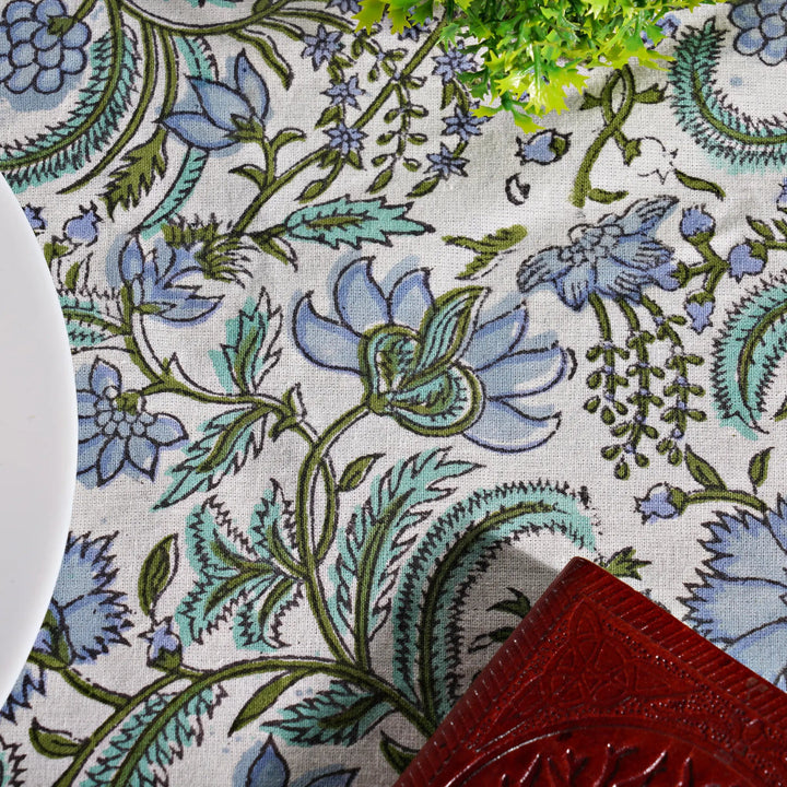 Close-up of a floral patterned fabric with blue and green flowers on a white background.