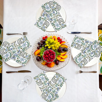 Table setting with patterned plates, napkins, and a fruit platter on a white tablecloth.