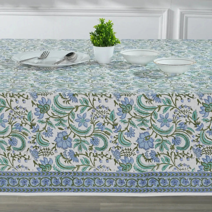 Decorative tablecloth with floral pattern on a set dining table.