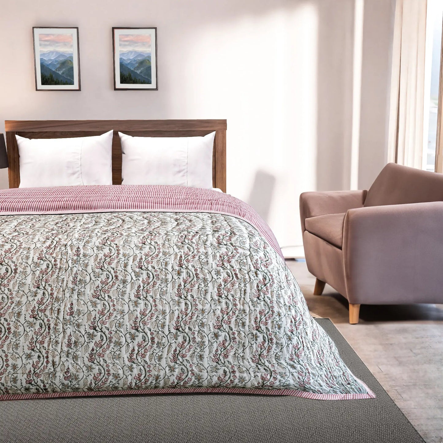 Bedroom with a bed covered in a patterned quilt, a chair, and framed pictures on the wall.