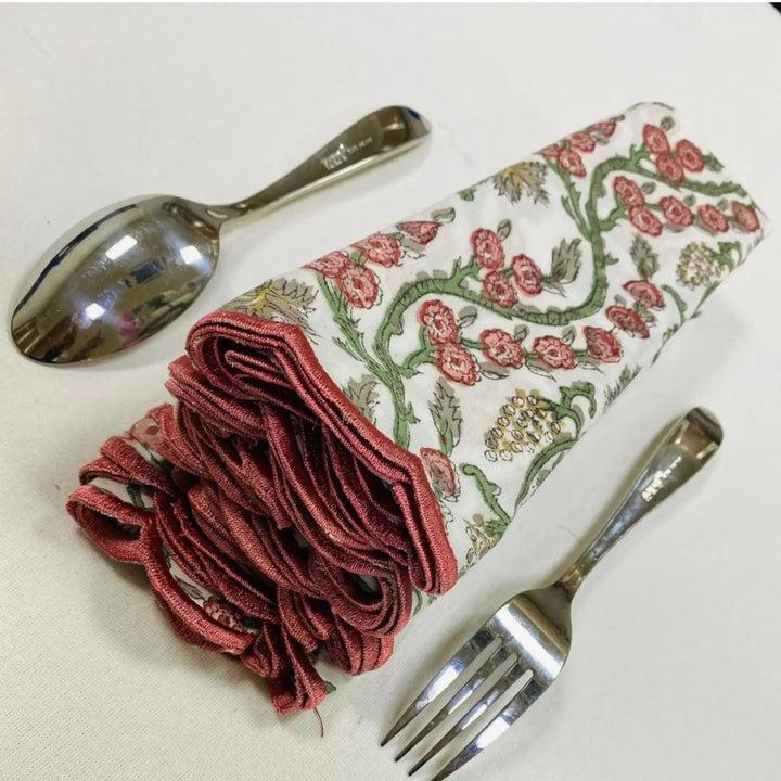 Floral-patterned napkin with red fabric, spoon, and fork on a white background