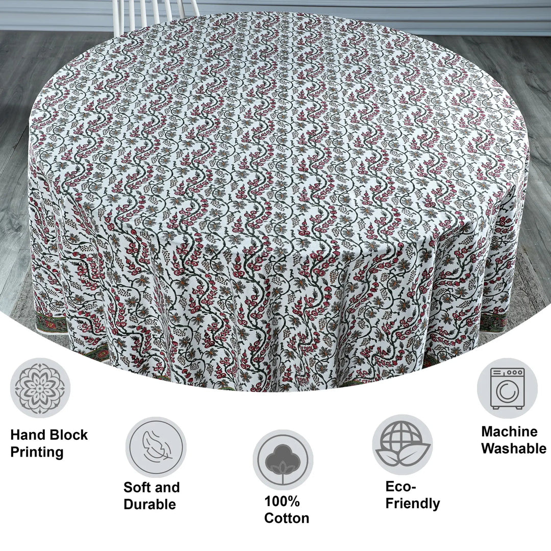 Round tablecloth with floral pattern on a wooden floor, featuring icons and text about material and care.