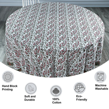 Round tablecloth with floral pattern on a wooden floor, featuring icons and text about material and care.