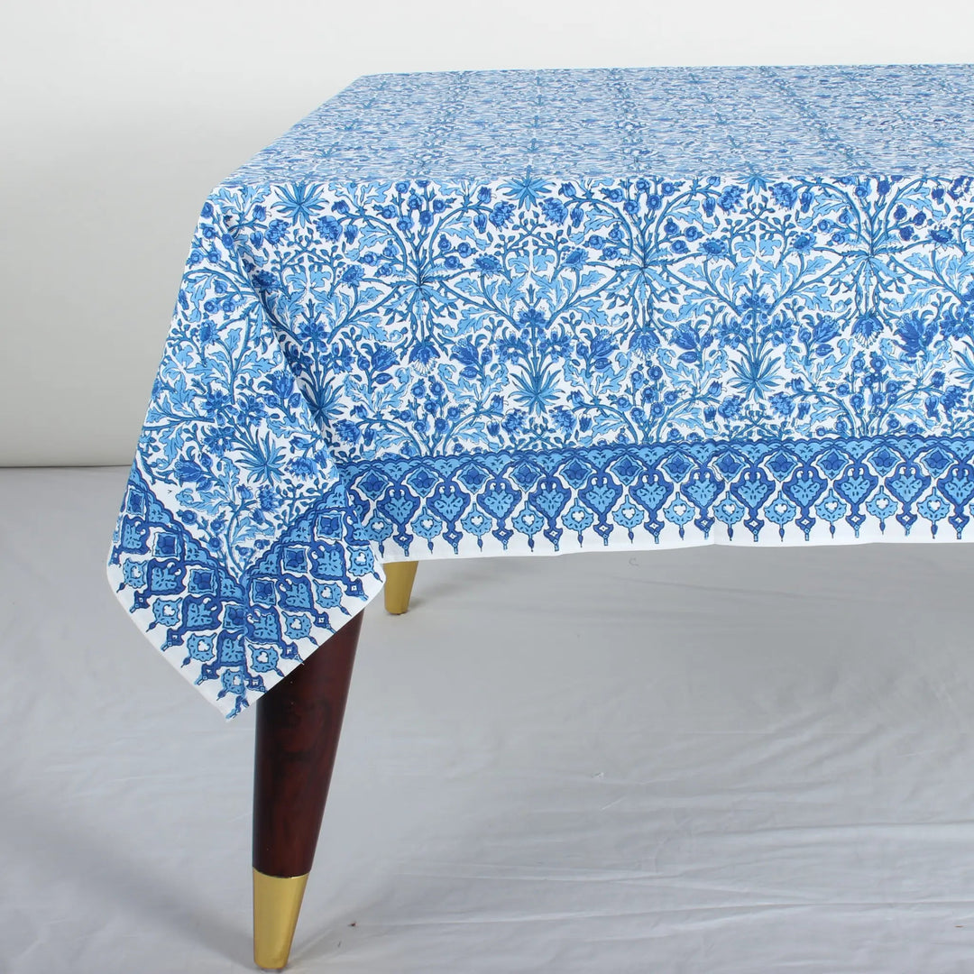 Blue floral patterned tablecloth on a wooden table with a white background