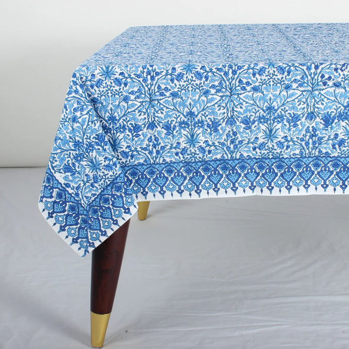 Blue floral patterned tablecloth on a wooden table with a white background