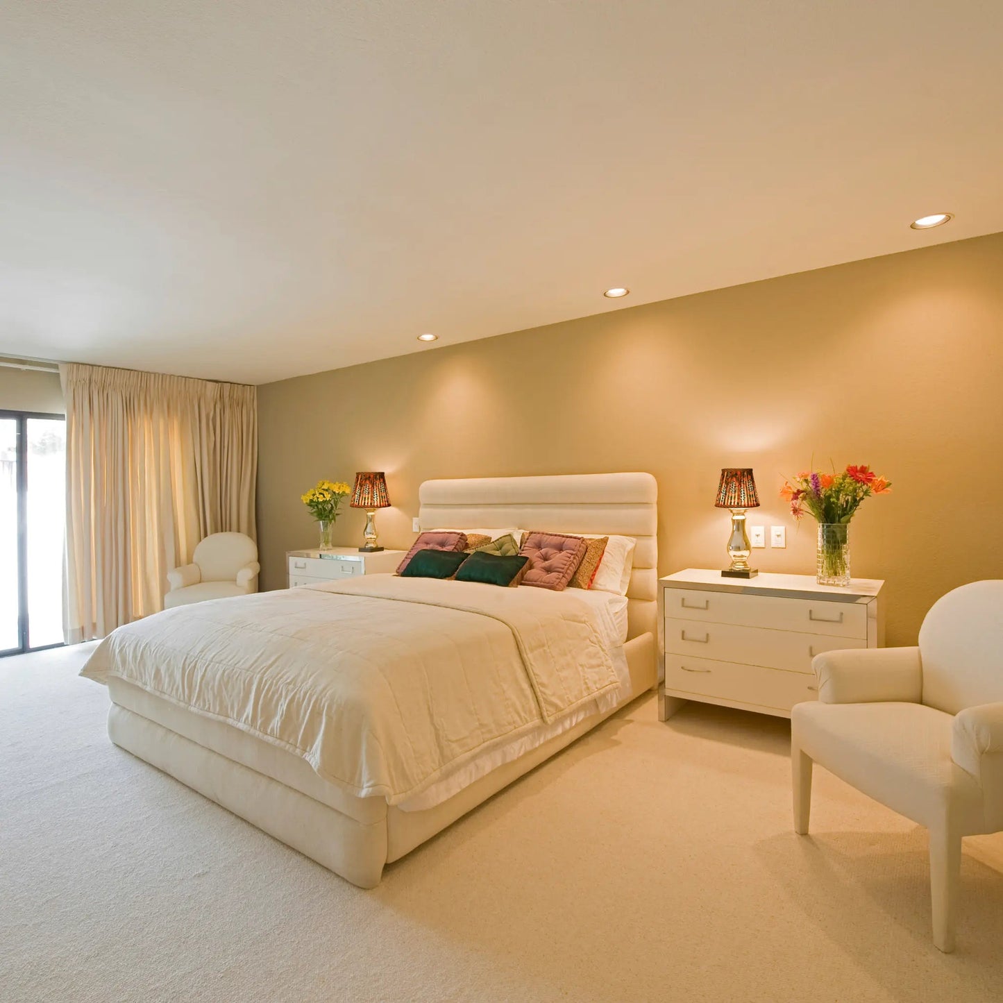 Neatly arranged bedroom with a bed, nightstands, and chairs.