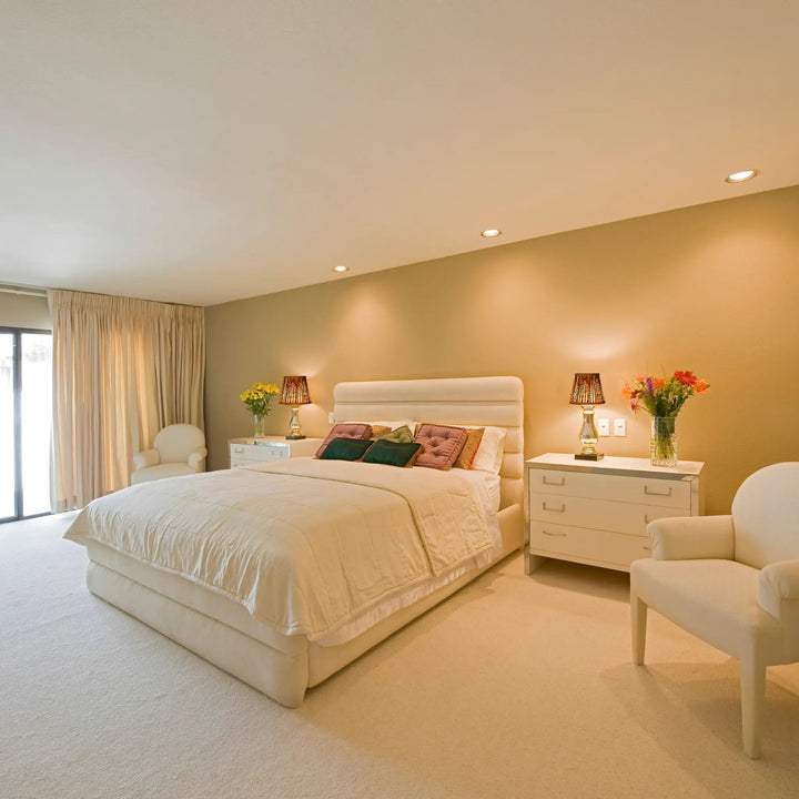 Neatly arranged bedroom with a bed, nightstands, and chairs.