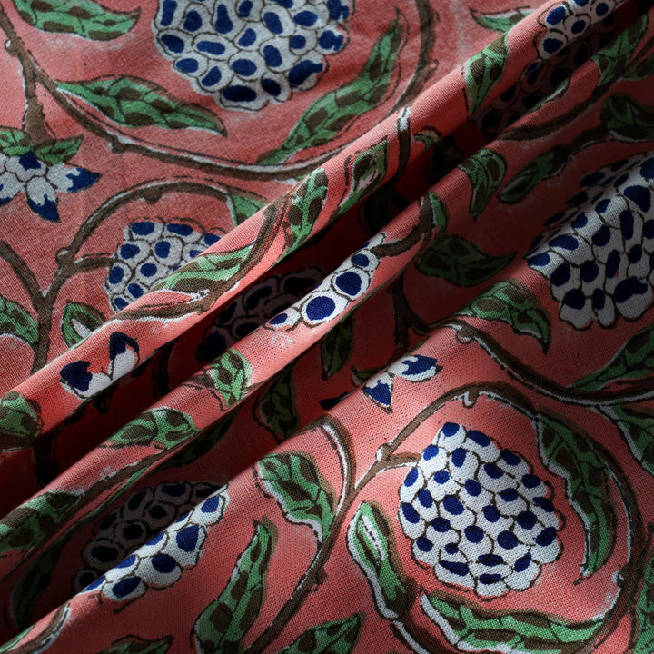 Close-up of floral patterned fabric with blue and green accents on a pink background
