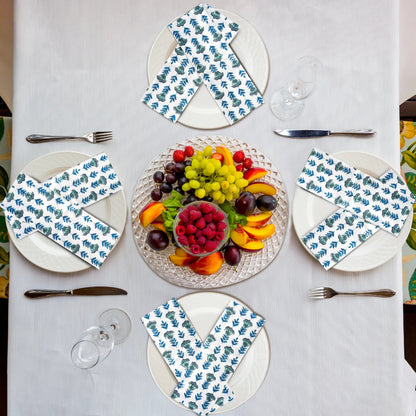 Table setting with plates, napkins, and a fruit platter on a white tablecloth.