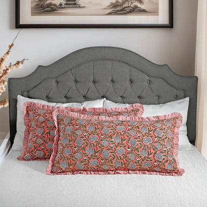 Large block print cotton pillows styled on gray upholstered bed.