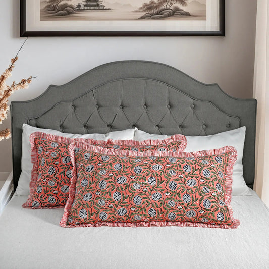 Large block print cotton pillows styled on gray upholstered bed.