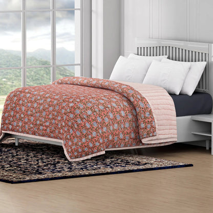 Bed with floral quilt and white pillows in a room with large windows and a view of mountains.