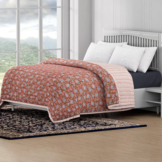 Bed with floral quilt and white pillows in a room with large windows and a view of mountains.