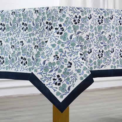 Floral patterned tablecloth with blue border on a wooden table.