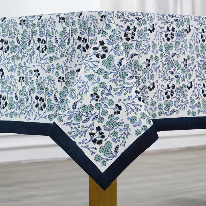 Floral patterned tablecloth with blue border on a wooden table.