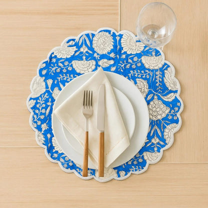 Decorative blue and white floral placemat with cutlery on a wooden surface