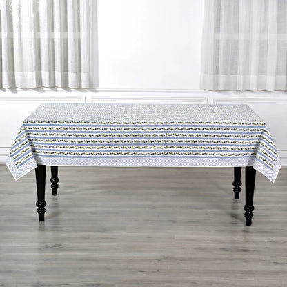Tablecloth with a subtle pattern on a wooden table in a room with white curtains.