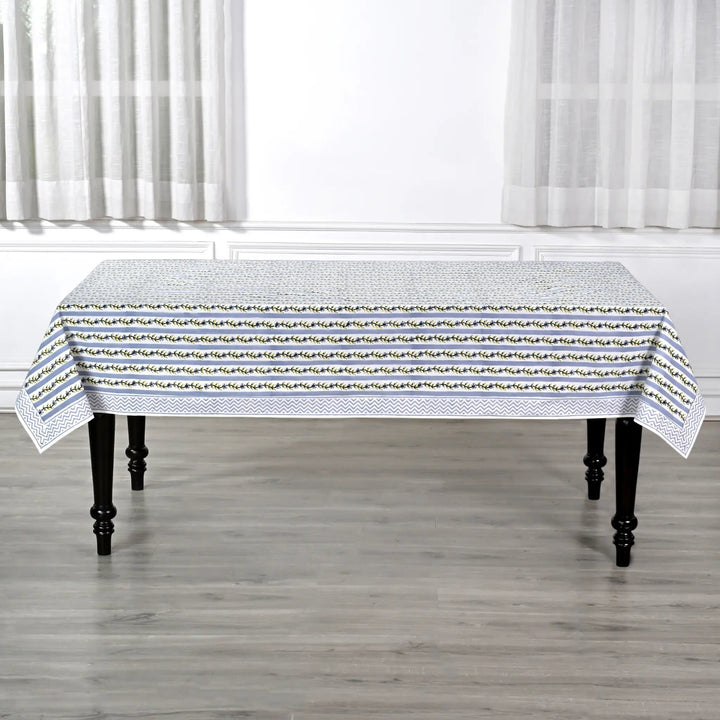 Tablecloth with a subtle pattern on a wooden table in a room with white curtains.