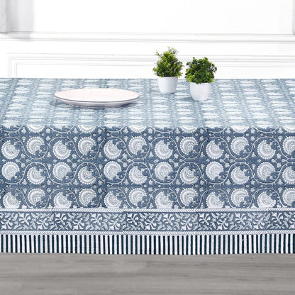Tablecloth with blue and white pattern on a table with plates and plants.