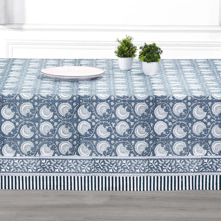 Tablecloth with blue and white pattern on a table with plates and plants.