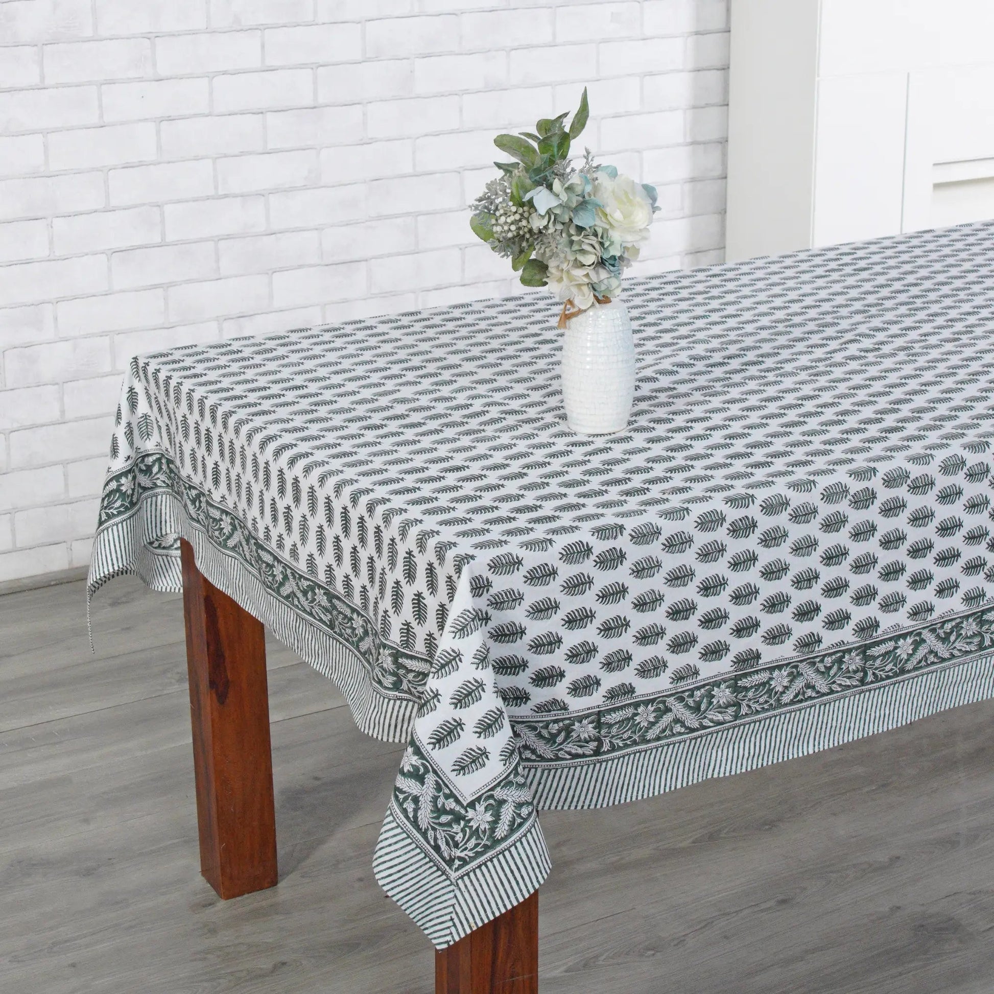 Tablecloth with a geometric pattern on a wooden table against a white brick wall.