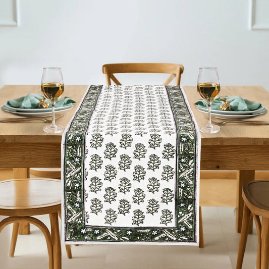 Dining table set with a decorative table runner featuring a leaf pattern.
