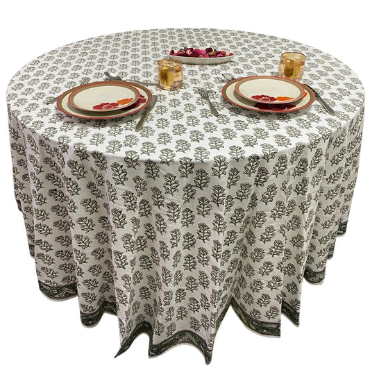 Round table with a patterned tablecloth, plates, and glasses on a white background