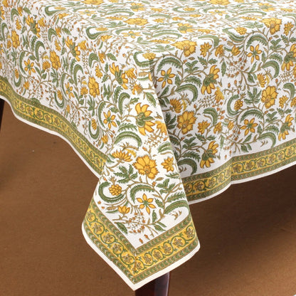 Floral patterned tablecloth with green and yellow design on a brown surface