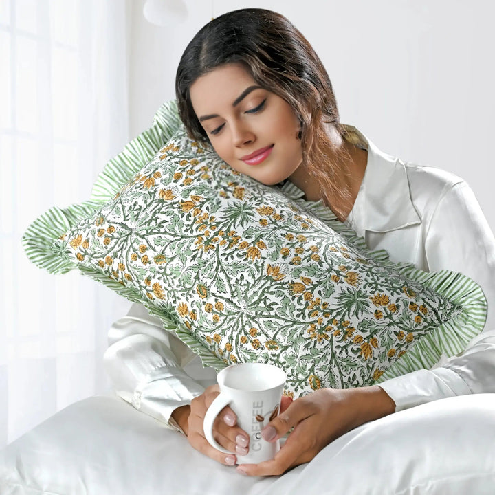 Woman holding a mug with a floral-patterned pillow behind her head on a white background