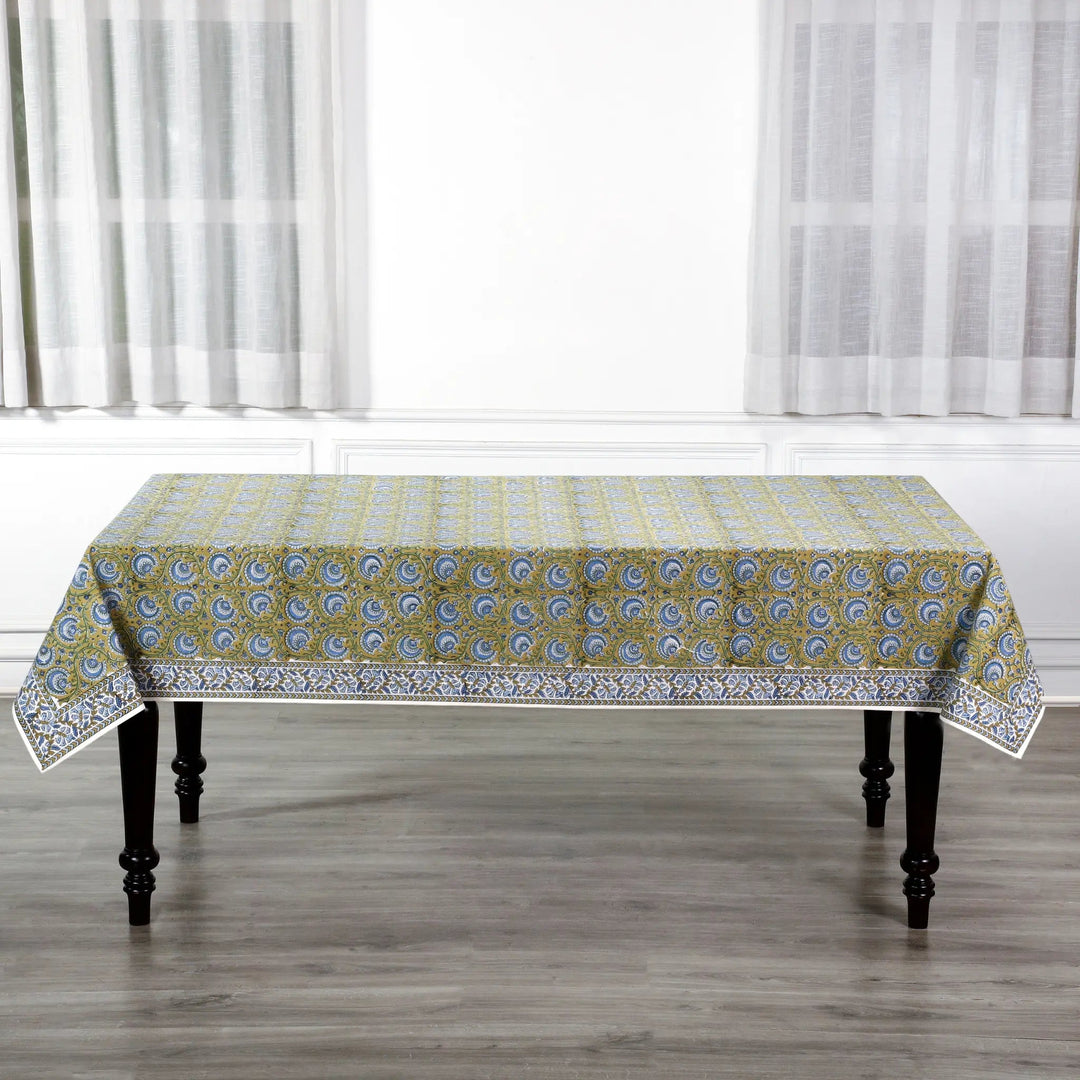 Patterned tablecloth on a wooden table with white curtains in the background