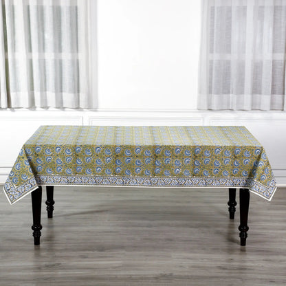 Patterned tablecloth on a wooden table with white curtains in the background