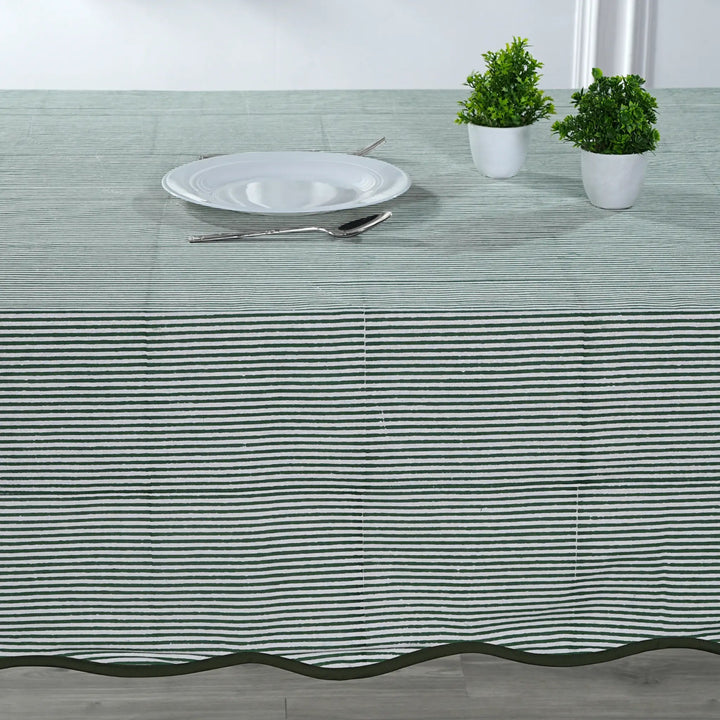 Tablecloth with black stripes on a table setting with a plate, cutlery, and plants.