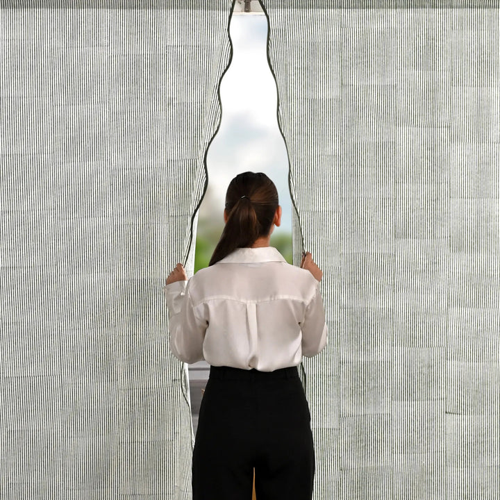 Person holding a large, wavy mirror against a textured wall.